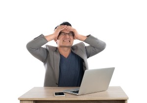 Stressed businessman work with laptop sitting at table isolated on white background.